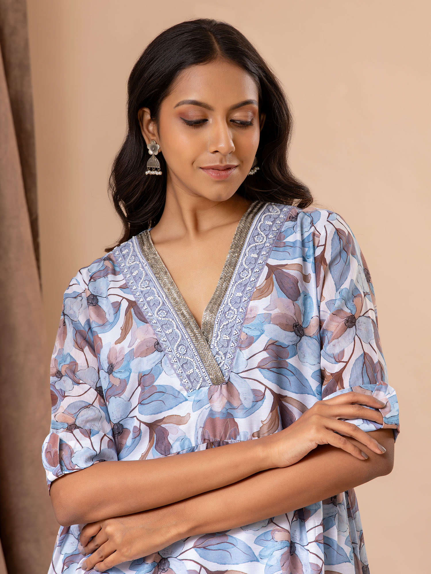 Printed top in shades of blues and browns with cutdana detailing on the neckline, paired with pants.